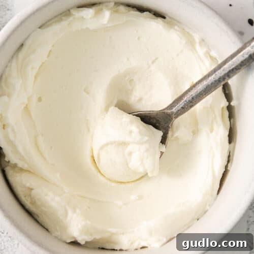 Wholesome whipped cream in a bowl with a spoon, perfectly smooth and inviting.