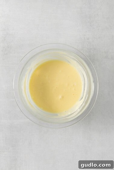 Decadent Cream Cheese Banana Bread Muffins 10 A bowl of yellow banana batter on a white surface.