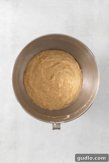 Decadent Cream Cheese Banana Bread Muffins 11 A metal bowl filled with completed muffin batter on a white surface.