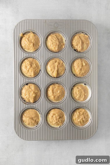 Decadent Cream Cheese Banana Bread Muffins 13 A muffin pan filled with layered muffin batter and cream cheese filling.