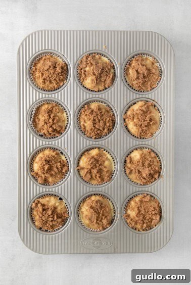 Decadent Cream Cheese Banana Bread Muffins 14 A muffin pan filled with muffins, each topped with a generous amount of crumb topping.