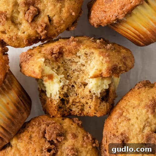 Decadent Cream Cheese Banana Bread Muffins 8 A group of muffins with a bite taken out of them, showing the cream cheese filling.