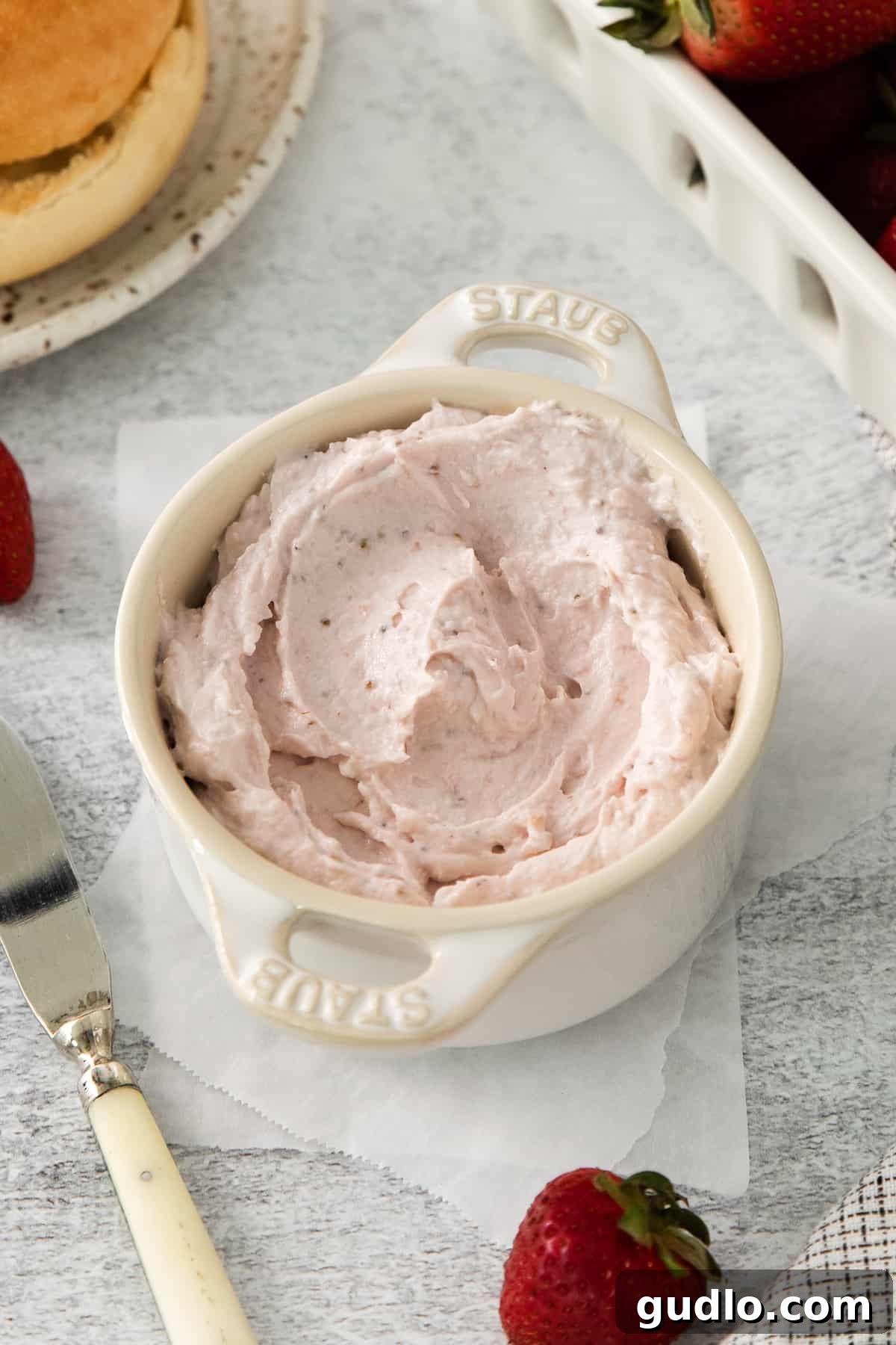 A rustic bowl filled with rich strawberry jam, accompanied by fresh strawberries and a fork, illustrating a delicious fruit spread.