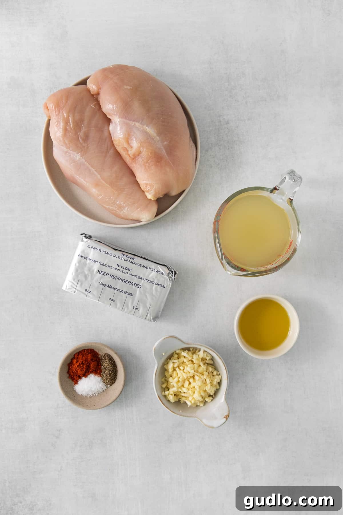 Crispy Garlic Chicken Delight 3 A selection of fresh chicken breast ingredients, including spices, oil, and garlic, neatly arranged on a white kitchen table, ready for cooking.