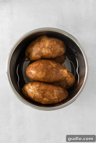 Ultimate Loaded Potato Bake 9 Boiled and roasted potato cubes in a metal bowl on a white background, ready for mashing.