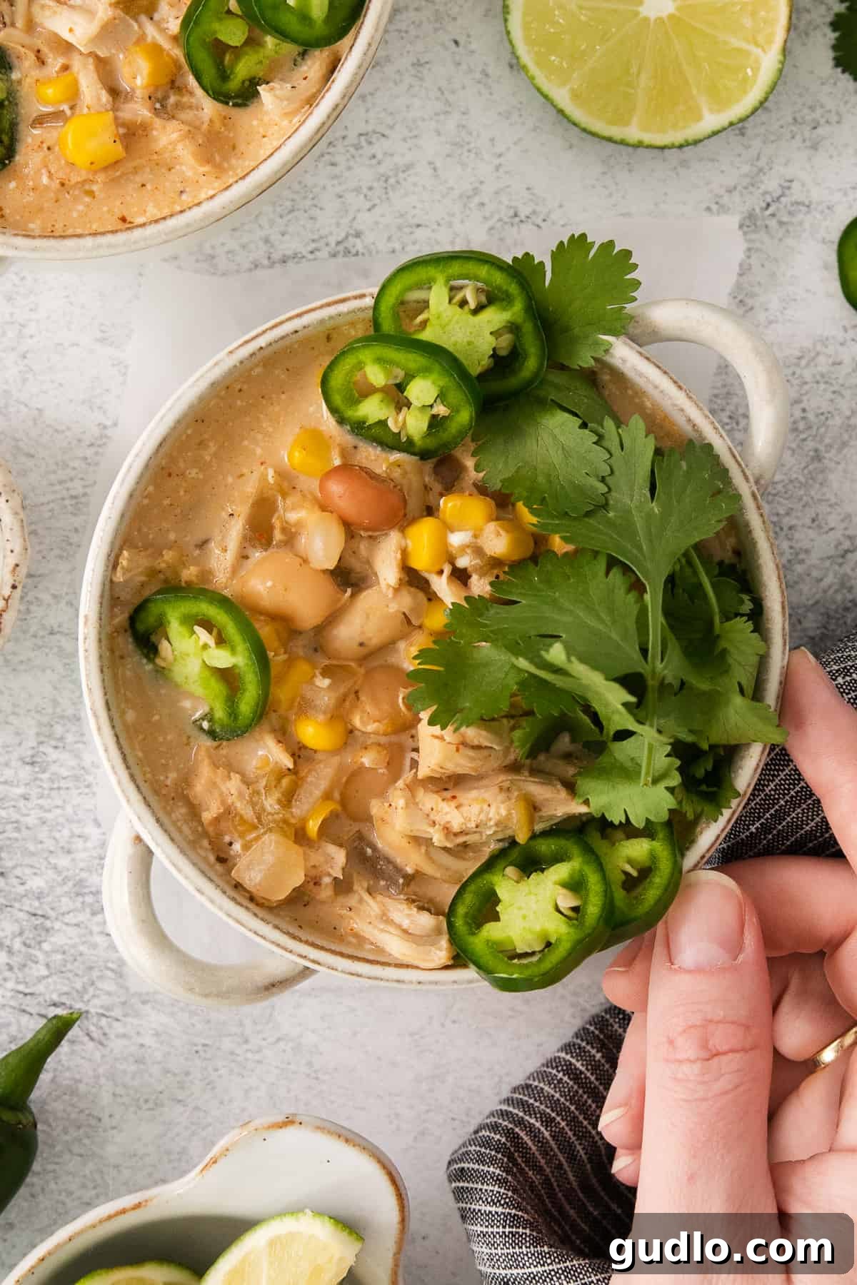 Creamy Slow Cooker White Chicken Chili 7 A cozy bowl of Mexican chicken soup, garnished with vibrant lime slices and spicy jalapeños, ready to be served.