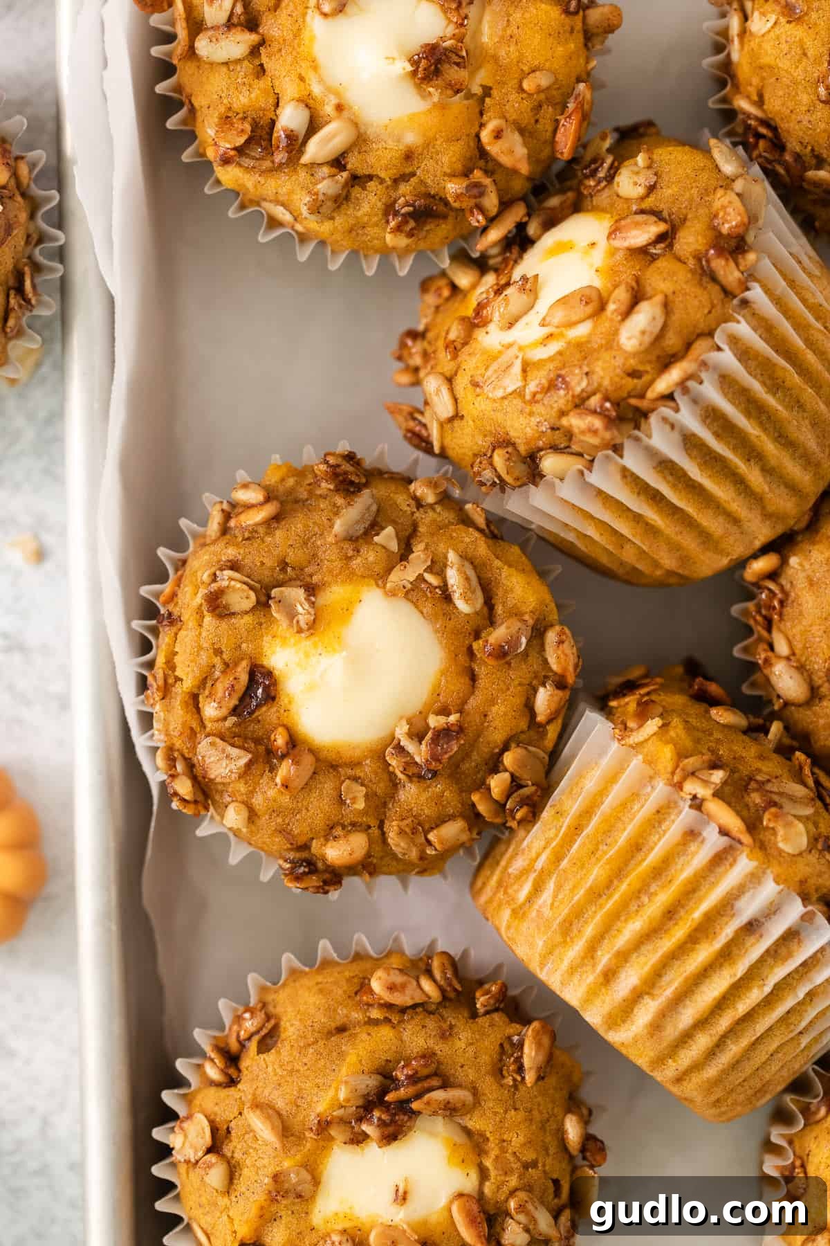 Cream Cheese Swirl Pumpkin Muffins 2 Golden-brown pumpkin buttermilk muffins on a baking sheet, showcasing their fluffy texture and enticing color, ready to be enjoyed.