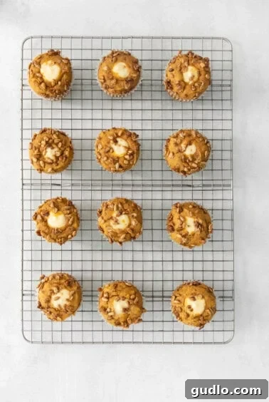 Cream Cheese Swirl Pumpkin Muffins 15 Freshly baked pumpkin muffins cooling on a metal rack, showing off their golden-brown tops and inviting texture.