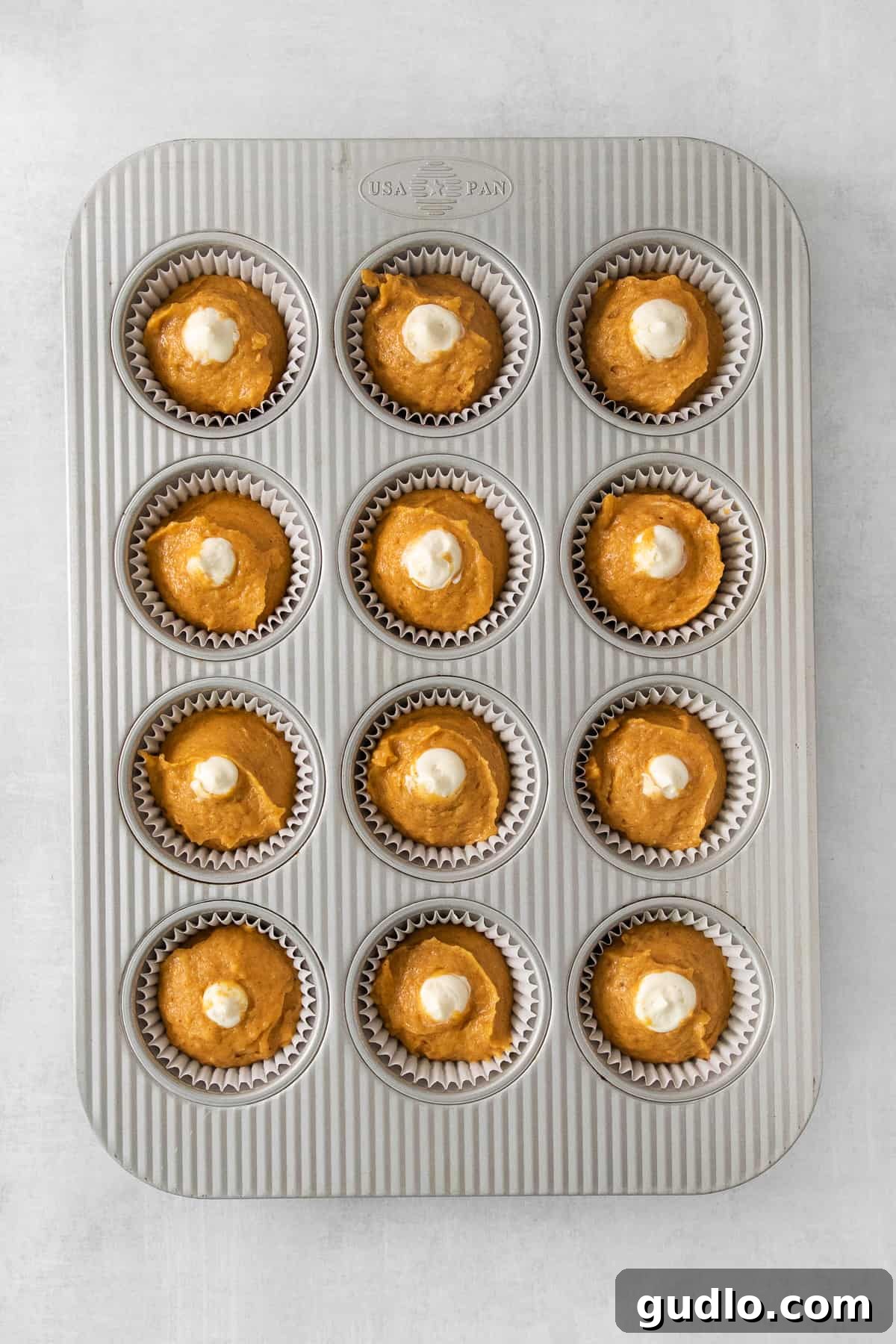 Cream Cheese Swirl Pumpkin Muffins 3 A tray of freshly baked pumpkin cupcakes, beautifully arranged in a muffin tin, highlighting their golden-brown tops and inviting texture.