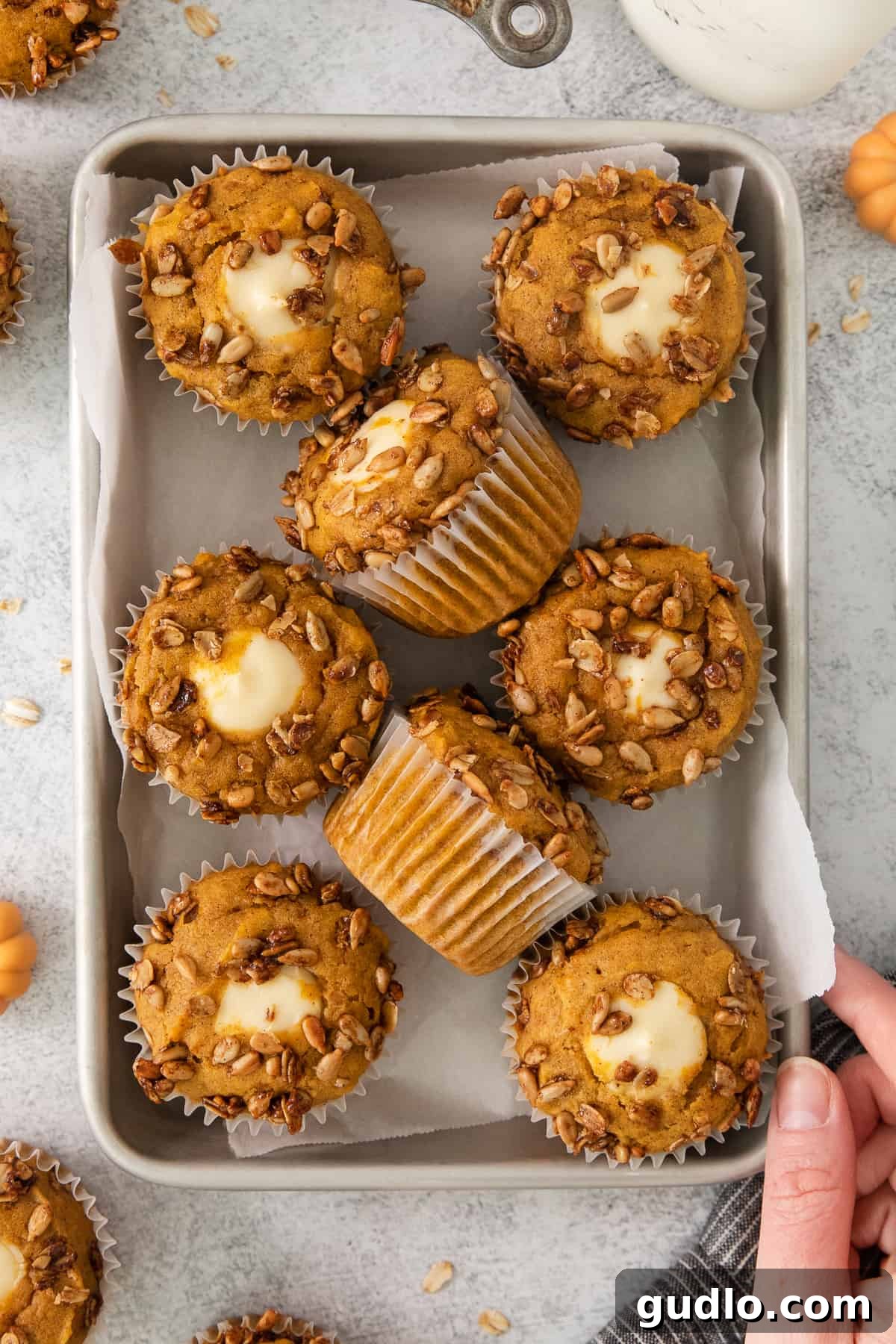 Cream Cheese Swirl Pumpkin Muffins 4 Close-up of baked pumpkin cheesecake muffins arranged on a baking sheet, featuring golden tops and a hint of cream cheese filling.