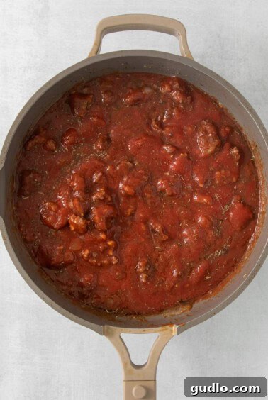 A pan full of rich tomato sauce mixed with meat and pasta.