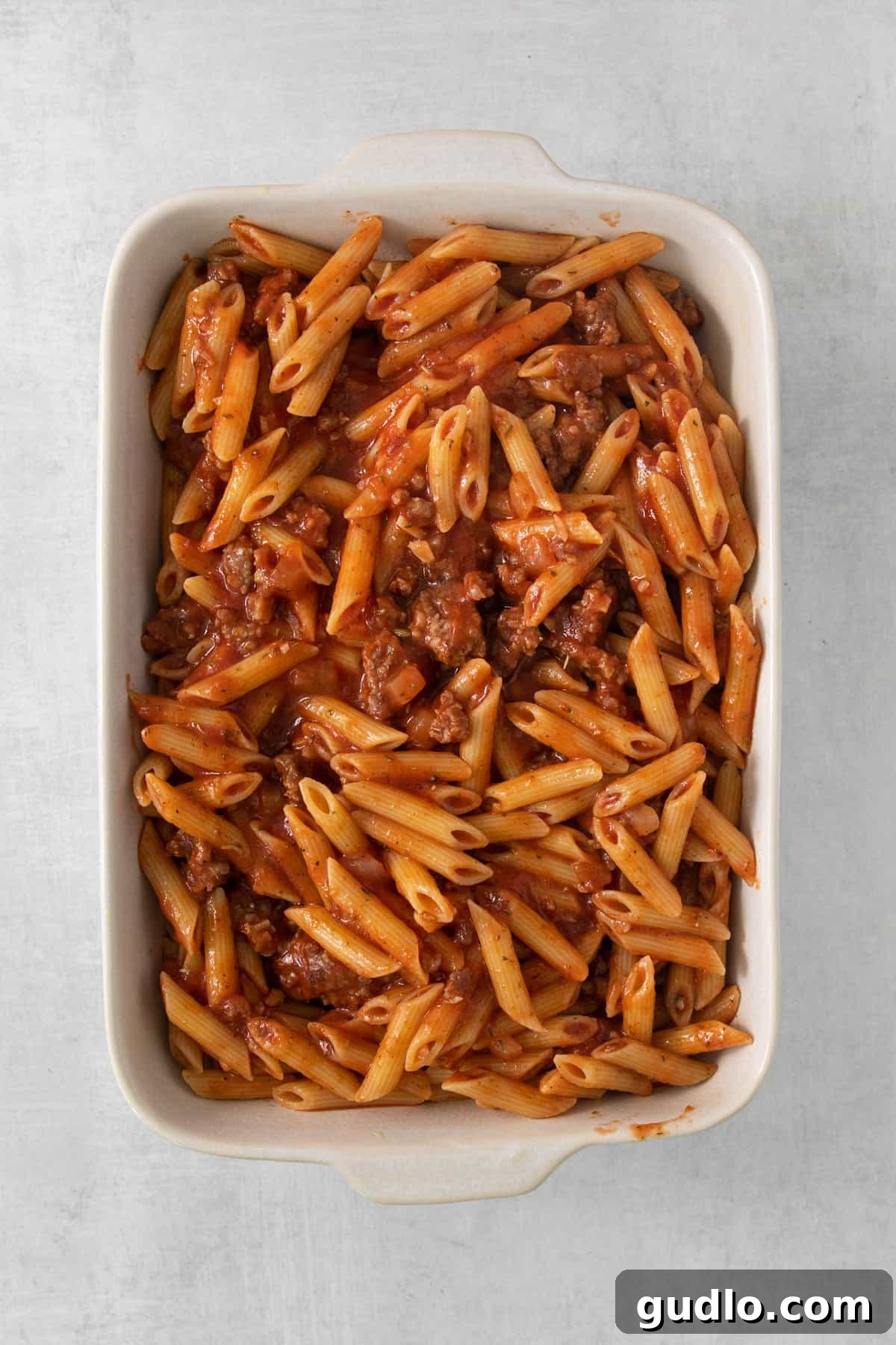 A rectangular baking dish filled with an appetizing pasta and meat mixture, ready for cheese and pepperoni.