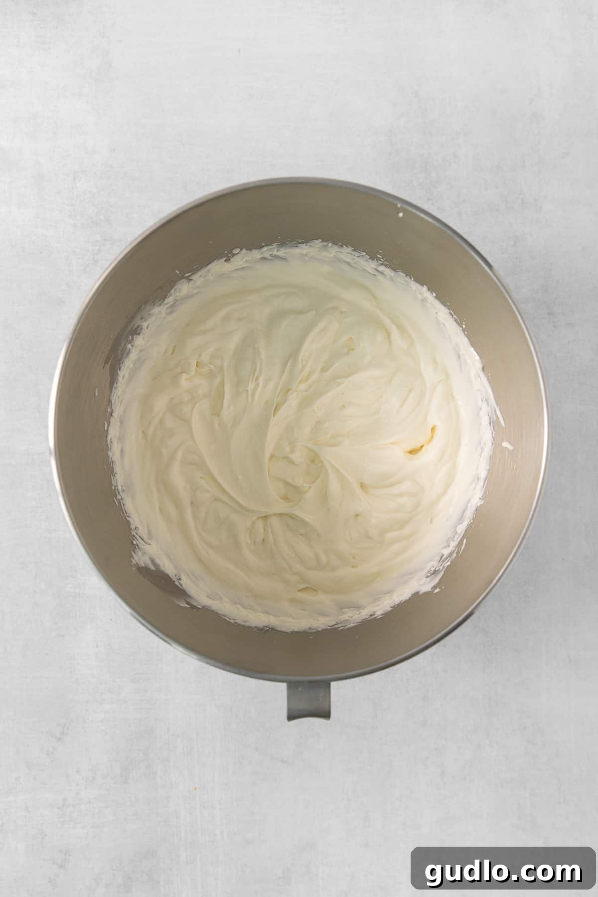 Decadent Banana Cream Cheese Pudding 4 A pristine white bowl overflowing with freshly made, fluffy whipped cream, indicating the creamy texture of the dessert.