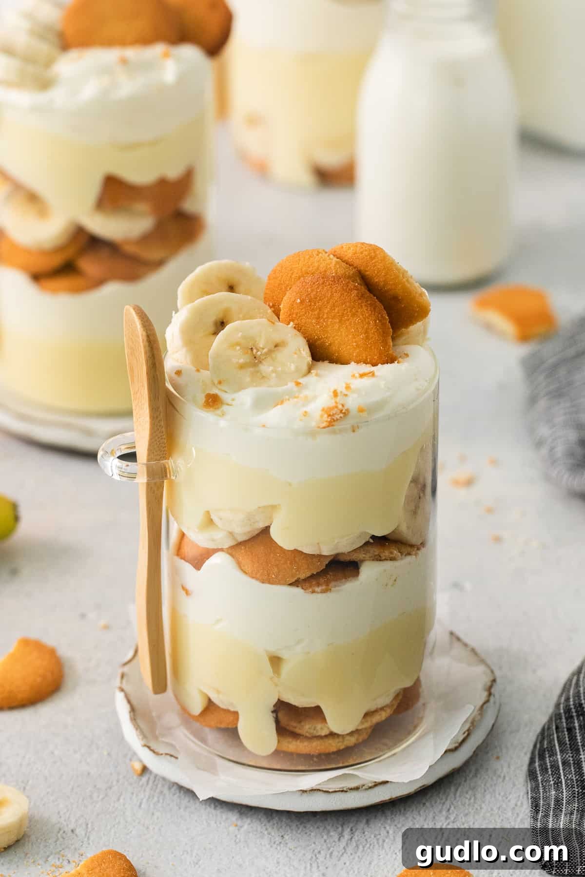Decadent Banana Cream Cheese Pudding 5 A close-up shot of a single serving of banana pudding, perfectly layered with cream and banana slices on a plate, garnished with a wafer.