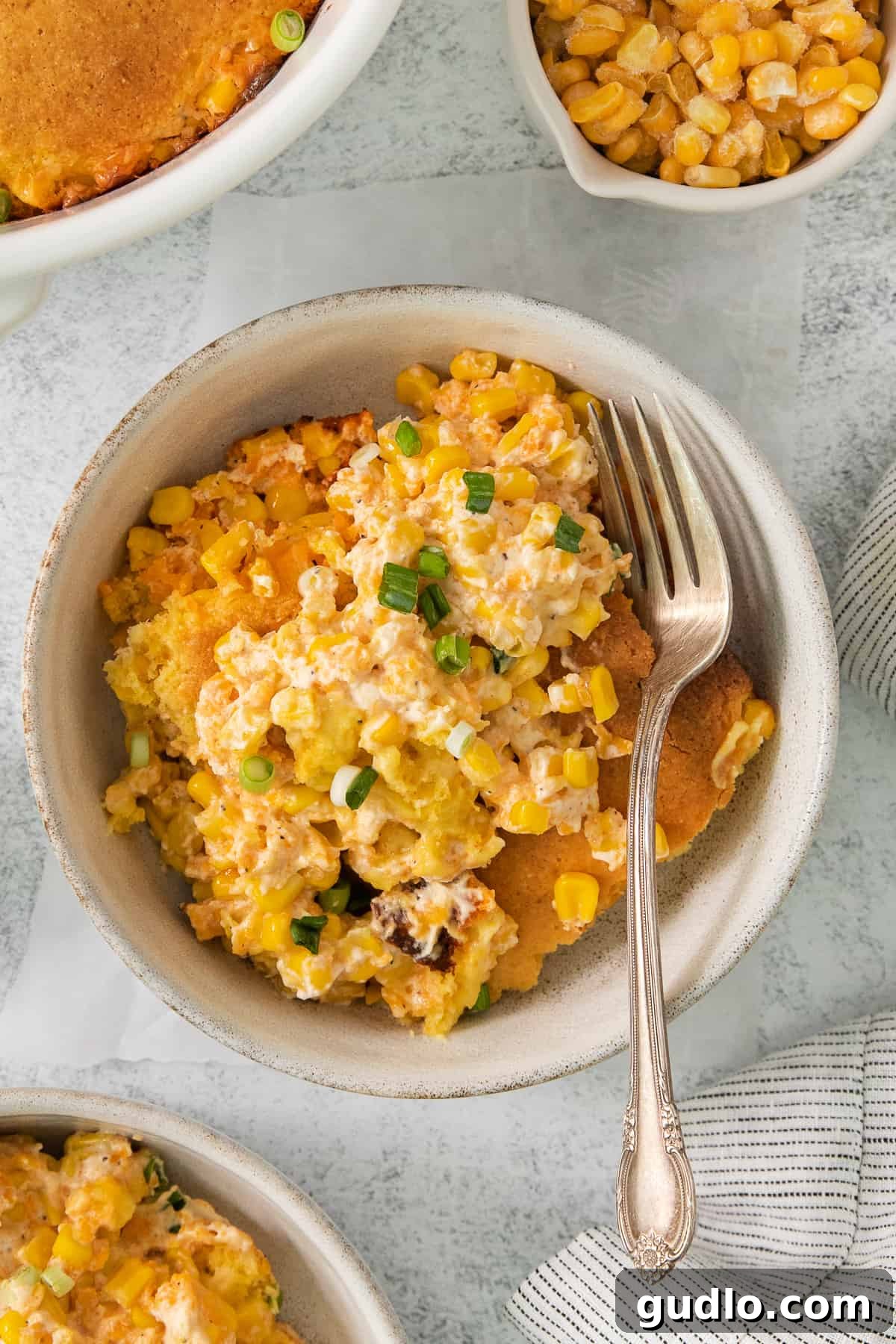 a bowl of corn casserole with a fork in it.