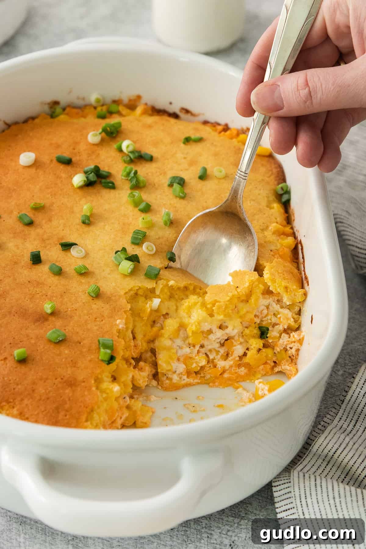 a person holding a spoon in a casserole dish.