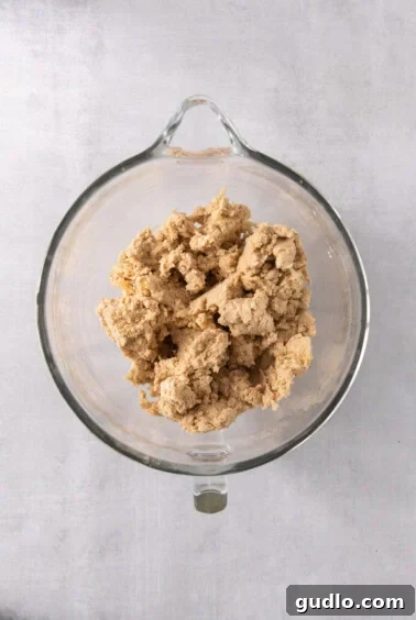 A glass bowl filled with cookie dough, with a caramel pressed into a portion, ready for baking.