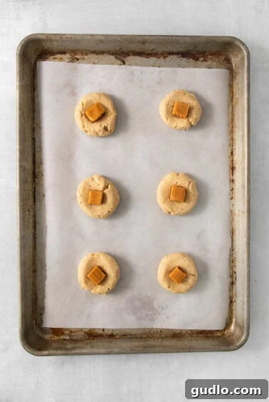 A baking sheet with six golden-brown cookies, freshly baked and cooling.