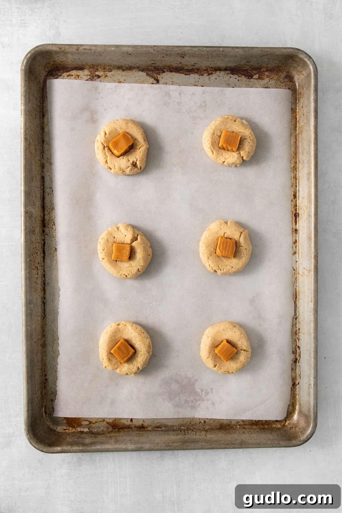 Caramel Apple Cheesecake Cookies 6 A baking sheet displaying six freshly baked caramel apple cookies, cooled and ready for frosting.