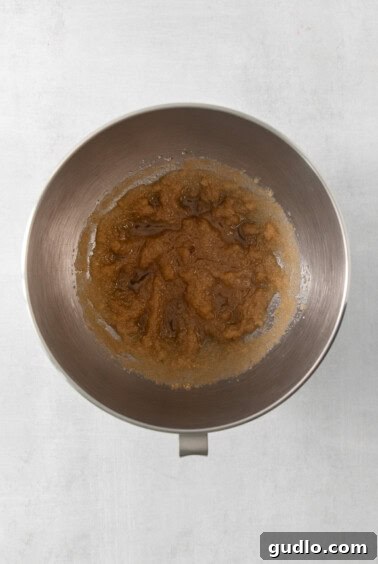 Swirled Apple Cream Cheese Coffee Cake 10 A metal mixing bowl containing avocado oil, granulated sugar, and brown sugar, being mixed by a stand mixer.