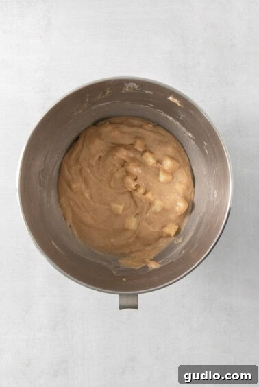 Swirled Apple Cream Cheese Coffee Cake 11 A metal mixing bowl filled with coffee cake batter, containing diced apples, after mixing.