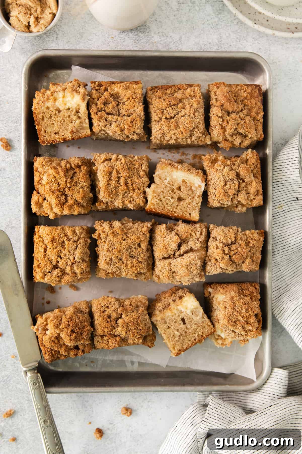 Swirled Apple Cream Cheese Coffee Cake 3 A baking pan filled with freshly baked Apple Cream Cheese Coffee Cake, sitting next to a steaming cup of coffee, ready to be served.