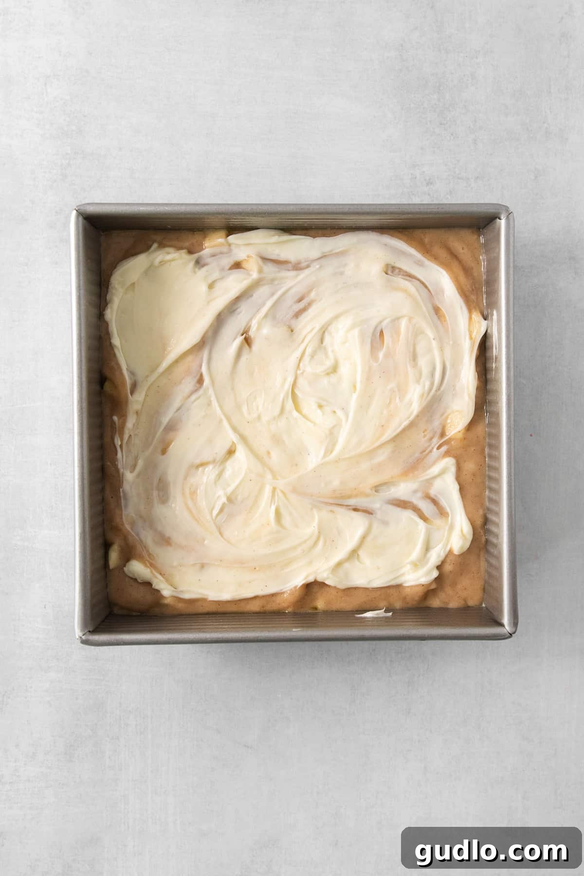 Swirled Apple Cream Cheese Coffee Cake 5 A baking pan filled with a smooth, white cream cheese filling spread over coffee cake batter, before the streusel.