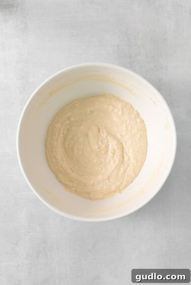 A white bowl containing a creamy mixture of cream cheese, sour cream, and spices, blended smoothly.