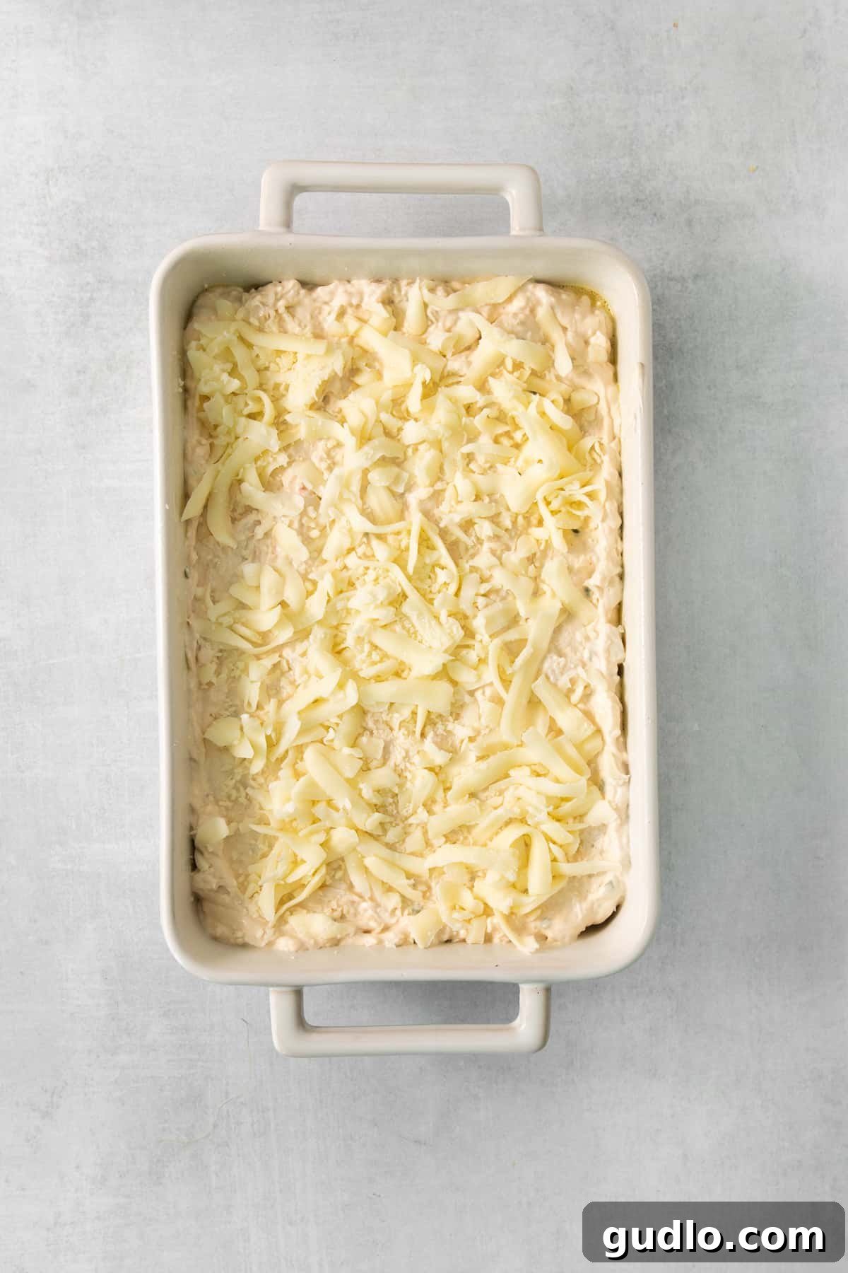 Deconstructed Crab Rangoon Dip 8 A golden-brown, bubbly layer of melted mozzarella cheese on top of the baked crab rangoon dip in a white ceramic baking dish, fresh out of the oven.