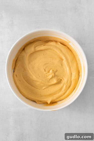 The pumpkin mousse mixture being whipped to a light and fluffy consistency in a bowl with a hand mixer.
