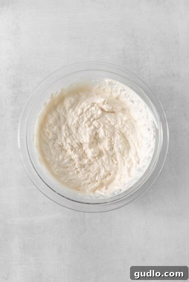 A bowl filled with freshly whipped cream, showing its soft, airy peaks, ready to be used as a topping.