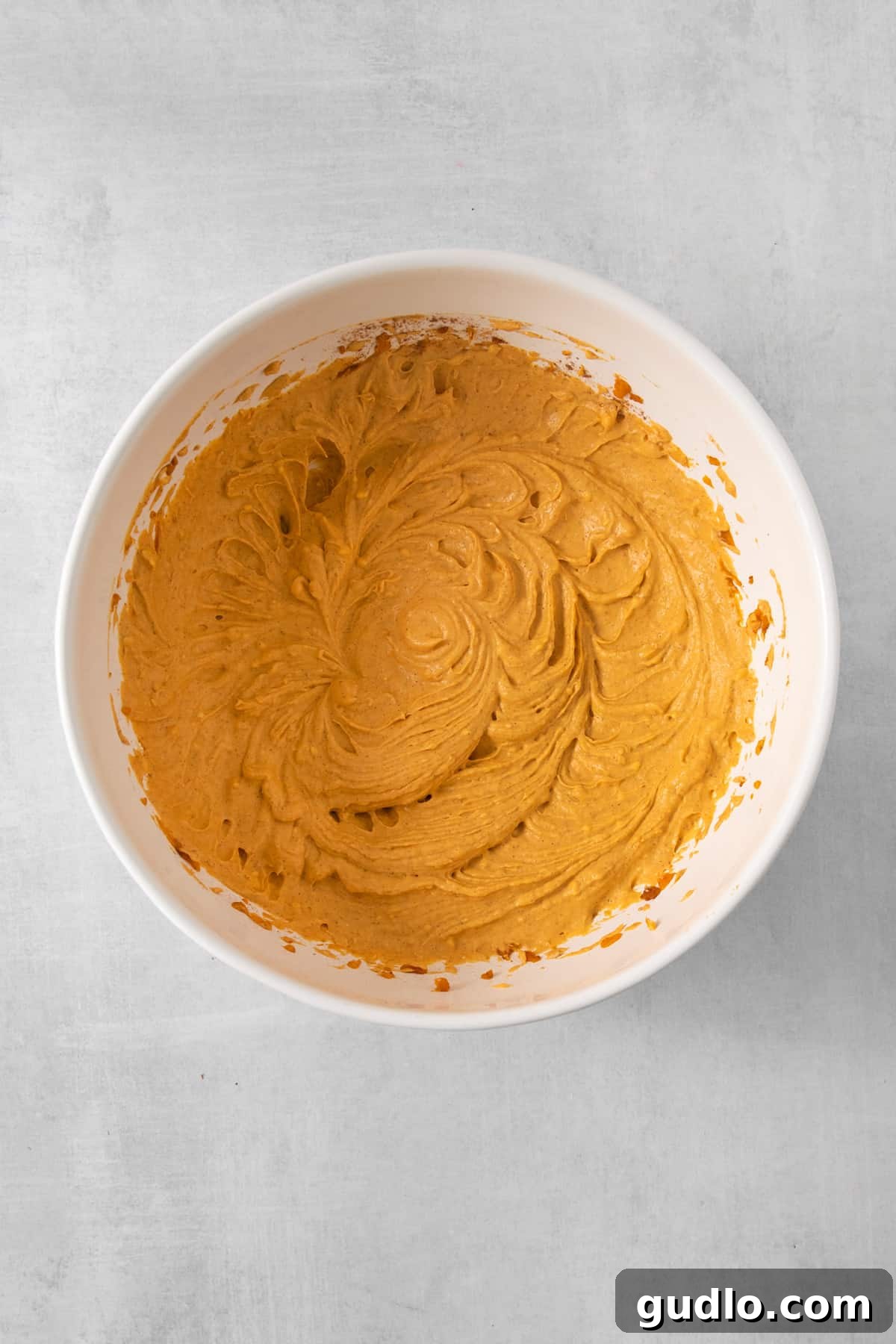 A bowl of creamy pumpkin mousse, beautifully smooth and vibrant, showcasing its delightful texture before being topped.