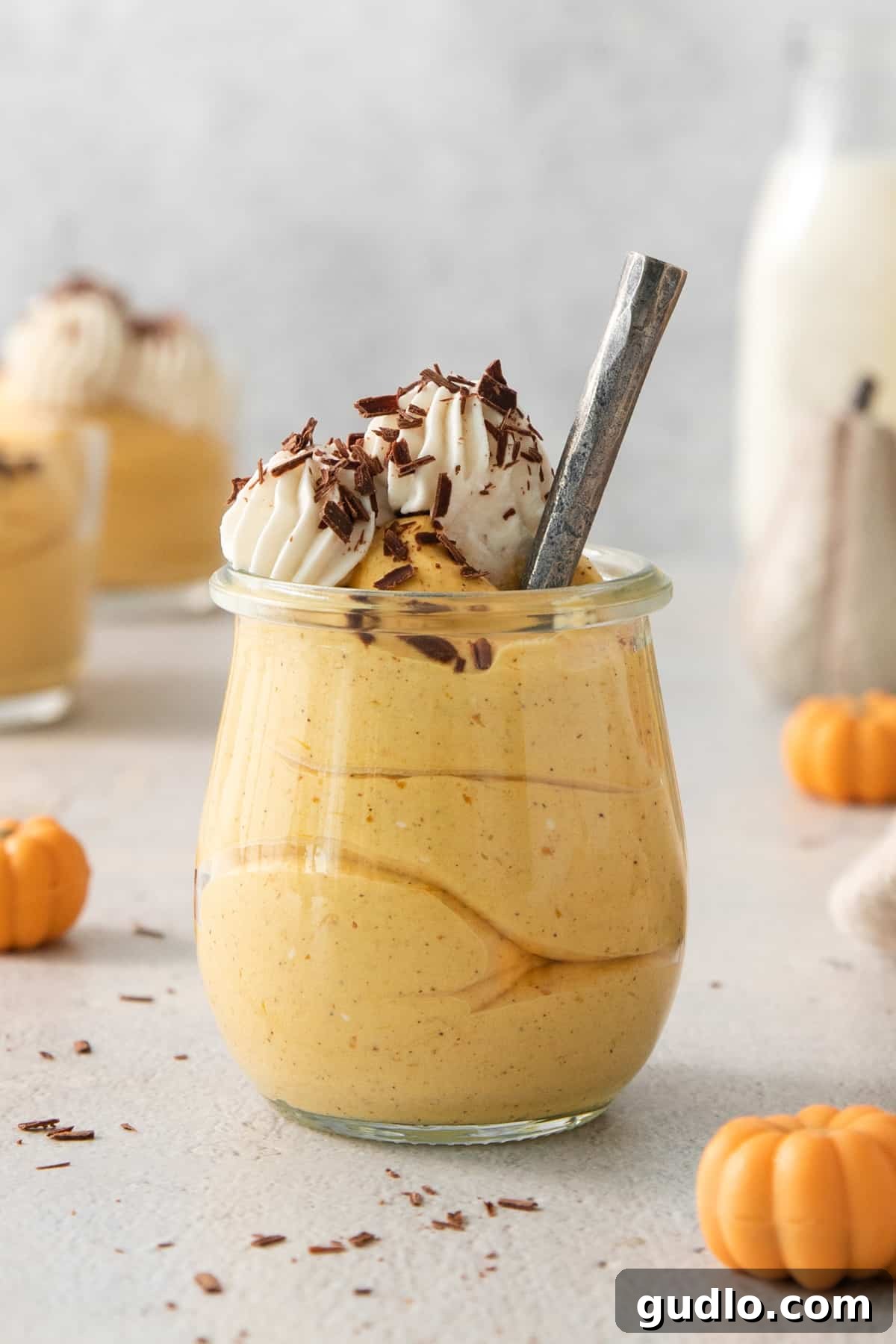 A single serving of pumpkin mousse in a glass, with a spoon nestled inside, inviting you to take the first delightful bite.