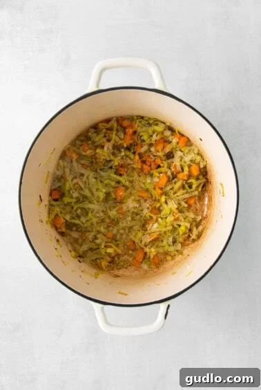 A pot filled with vibrant carrots and leeks, gently sautéing in olive oil, ready for the next step of soup preparation.