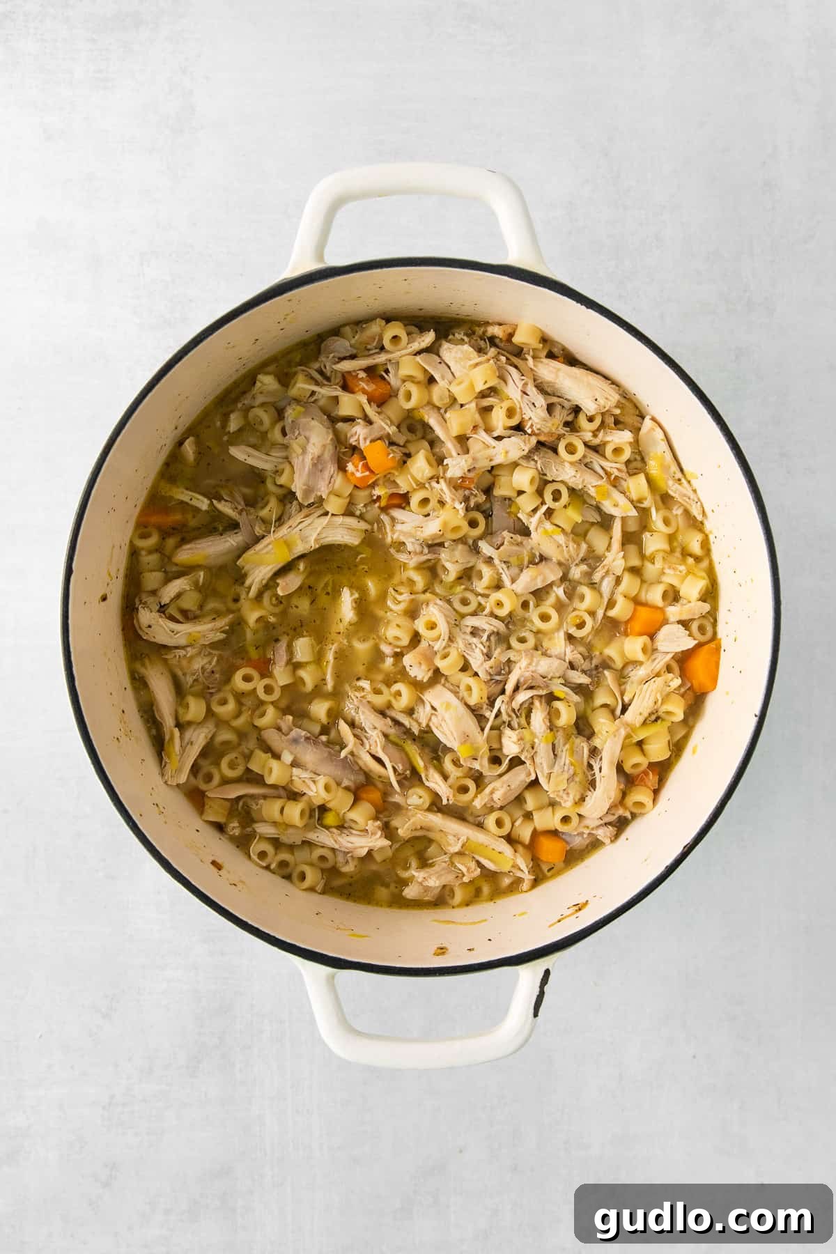 Golden Cream Chicken 5 A large white pot on a stovetop, filled with simmering creamy chicken noodle soup, with steam gently rising, highlighting its readiness to be served.