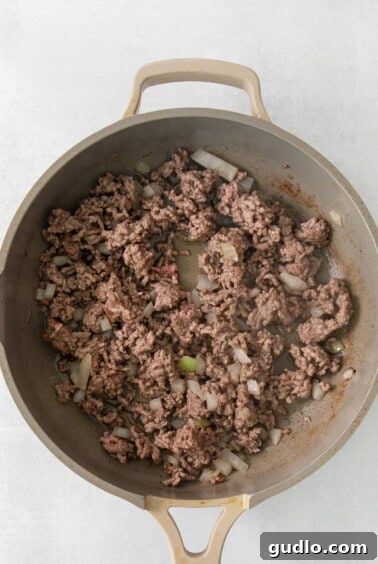Ultimate Chili Mac and Cheese 10 A skillet filled with browning ground beef and onions, the beginnings of a delicious meal.