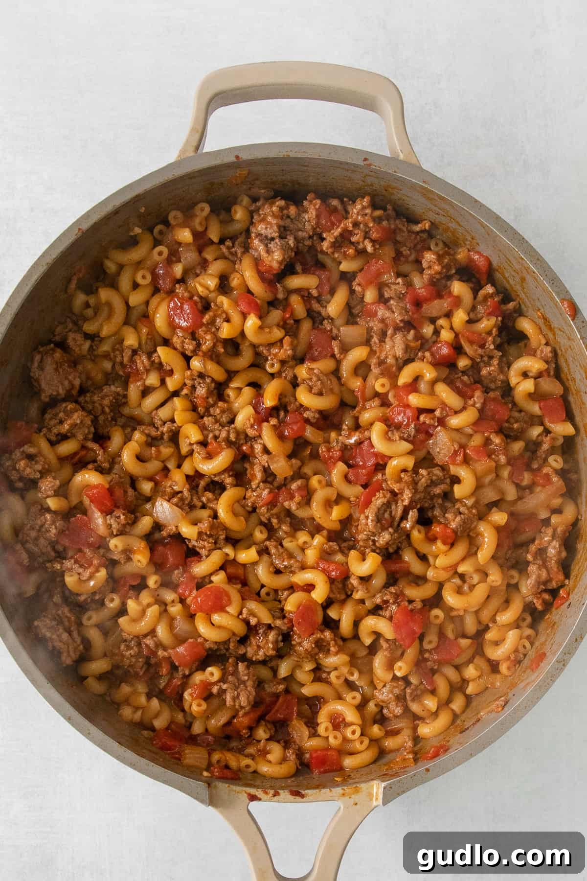 Ultimate Chili Mac and Cheese 3 A robust skillet filled with perfectly cooked pasta and ground meat, simmering in a rich, savory sauce.