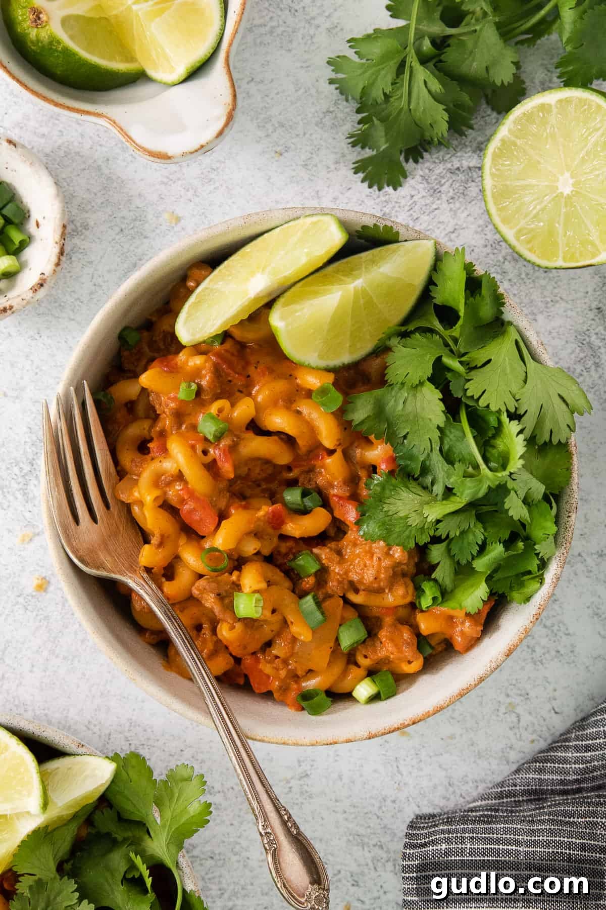 Ultimate Chili Mac and Cheese 7 A inviting bowl of Mexican-style macaroni and cheese, garnished with vibrant lime wedges and fresh cilantro.