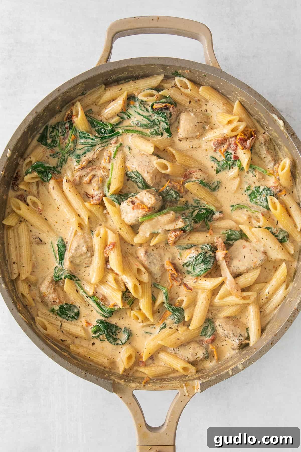 Chicken and spinach pasta in a skillet, freshly tossed with the creamy sauce.