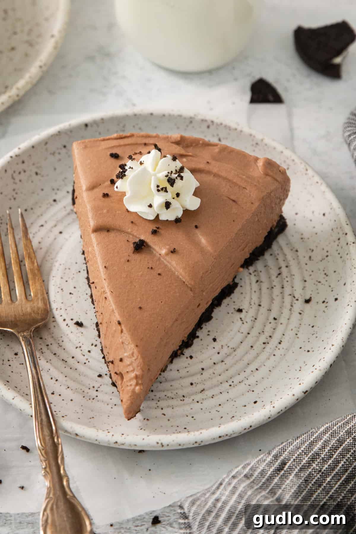 Divine Chocolate Cloud Pie 2 A perfectly sliced piece of chocolate mousse pie on a pristine white plate, showcasing its creamy layers and dark chocolate crust.