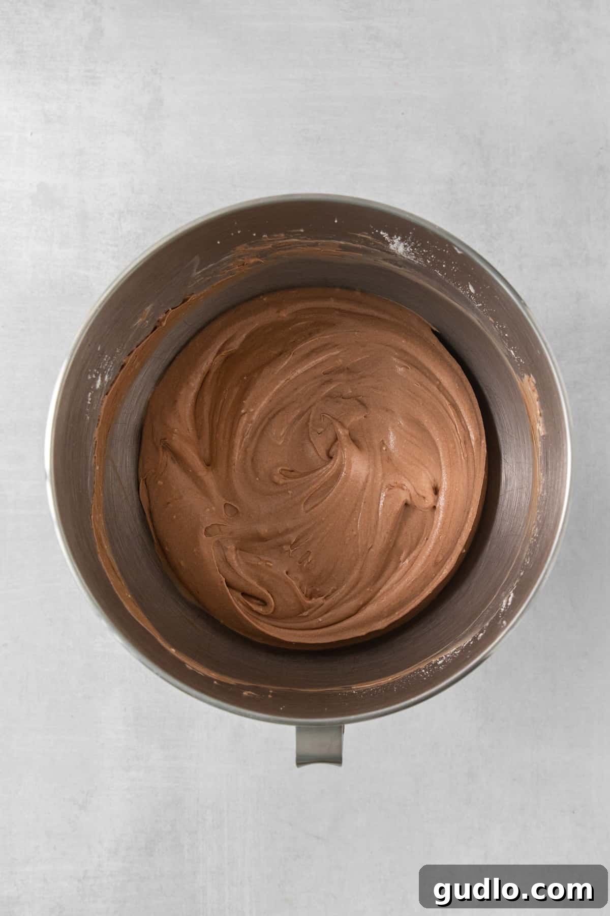 Divine Chocolate Cloud Pie 4 A metal bowl brimming with rich, velvety chocolate frosting, showcasing a luxurious texture.