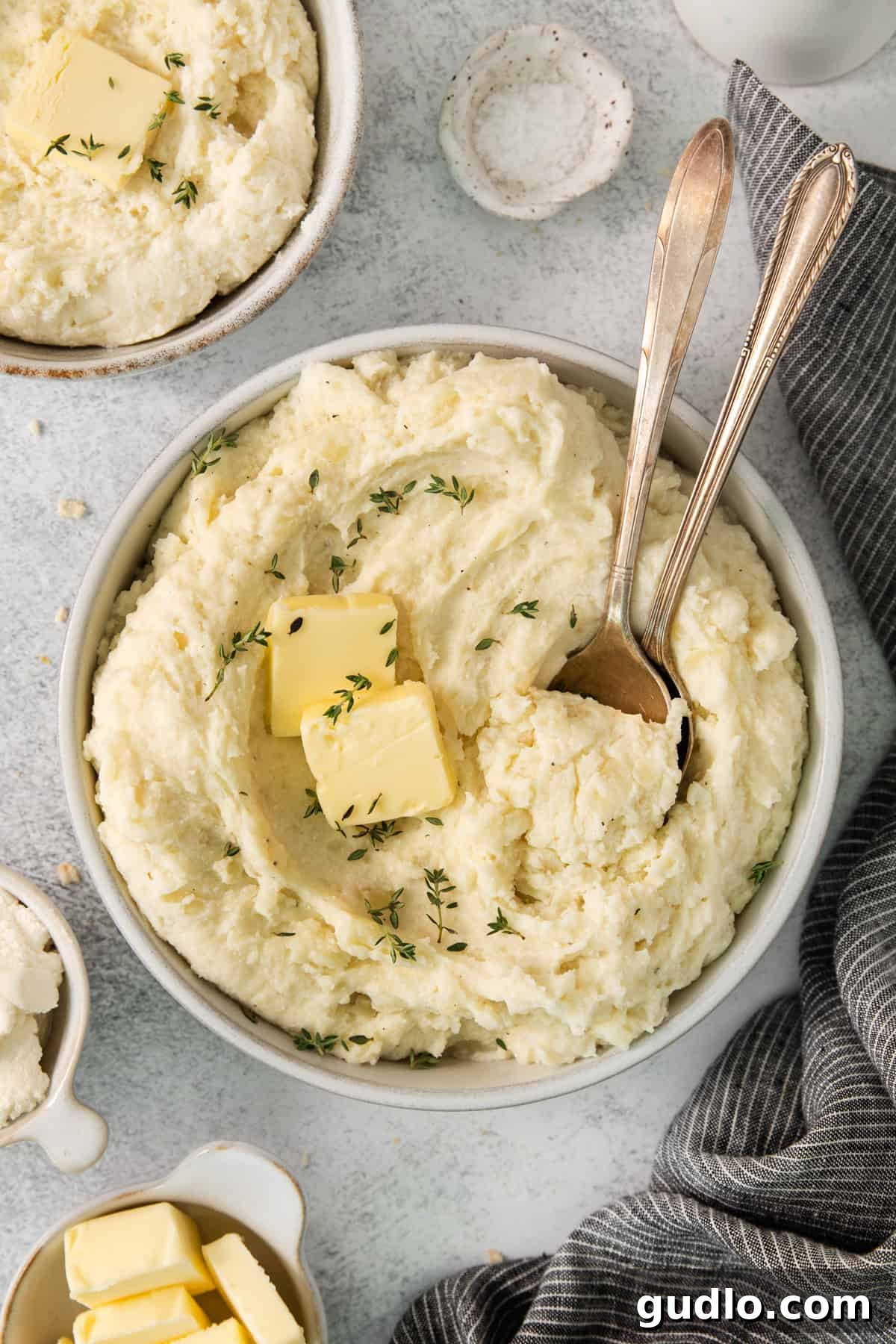 Luxurious Garlic Mashed Potatoes 2 Two bowls of fluffy garlic mashed potatoes, garnished with melted butter and fresh herbs.