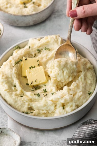 Luxurious Garlic Mashed Potatoes 11 A serving of creamy garlic mashed potatoes in a bowl, with a spoon ready to scoop.