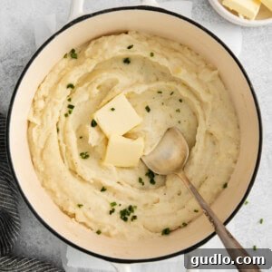 mashed potatoes in a pot with butter and parsley.