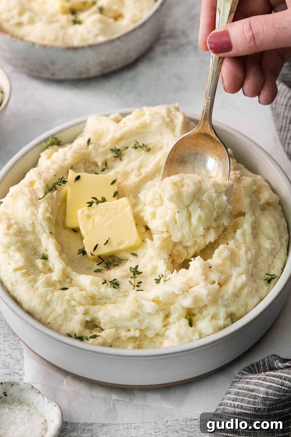 Luxurious Garlic Mashed Potatoes 6 A serving bowl filled with creamy mashed potatoes, garnished with a pat of butter and fresh herbs.