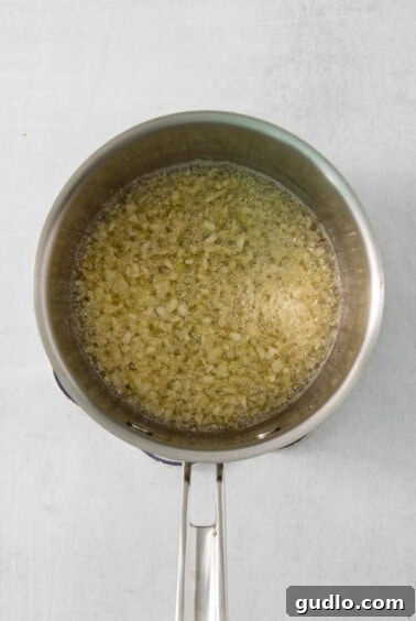 Luxurious Garlic Mashed Potatoes 9 Minced garlic sizzling in melted butter in a frying pan.