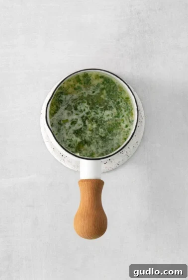 A small saucepan with butter, minced garlic, and chives, gently melting and infusing together.