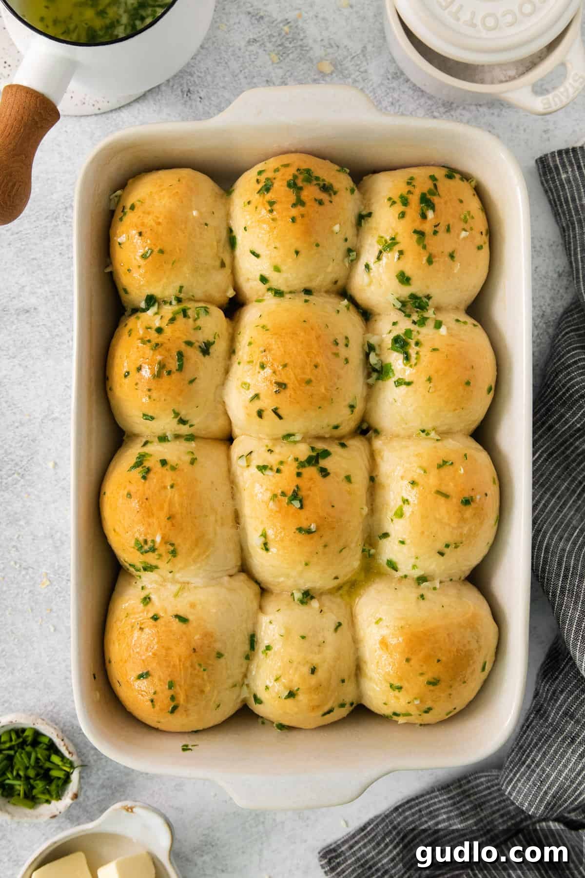 Savory Chive Garlic Cream Cheese Bites 5 Baked cheesy garlic rolls in a white baking dish, brushed with garlic butter and garnished with fresh parsley.