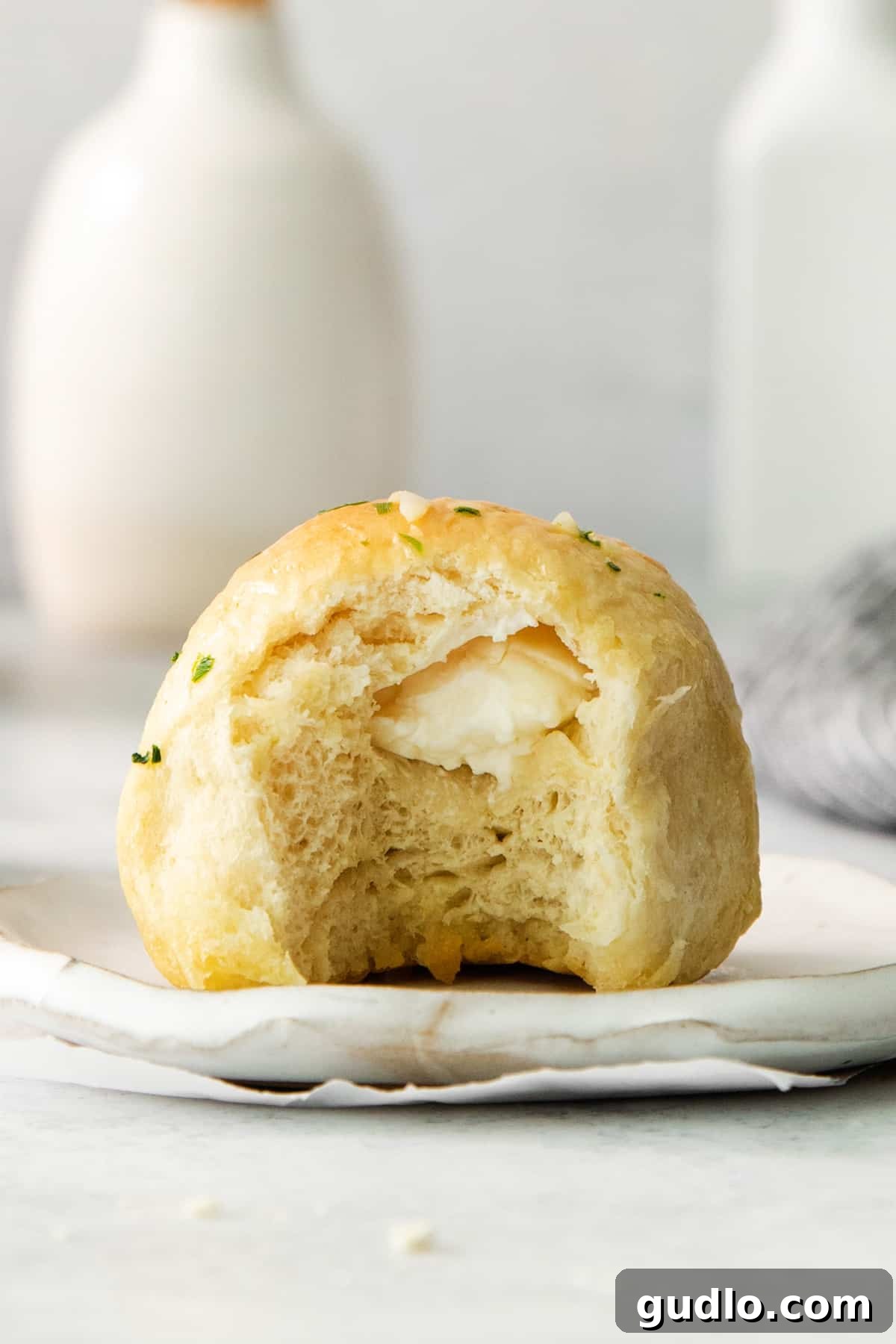 Savory Chive Garlic Cream Cheese Bites 6 A freshly baked, fluffy loaf of bread on a plate with a bite taken out, revealing its soft interior.