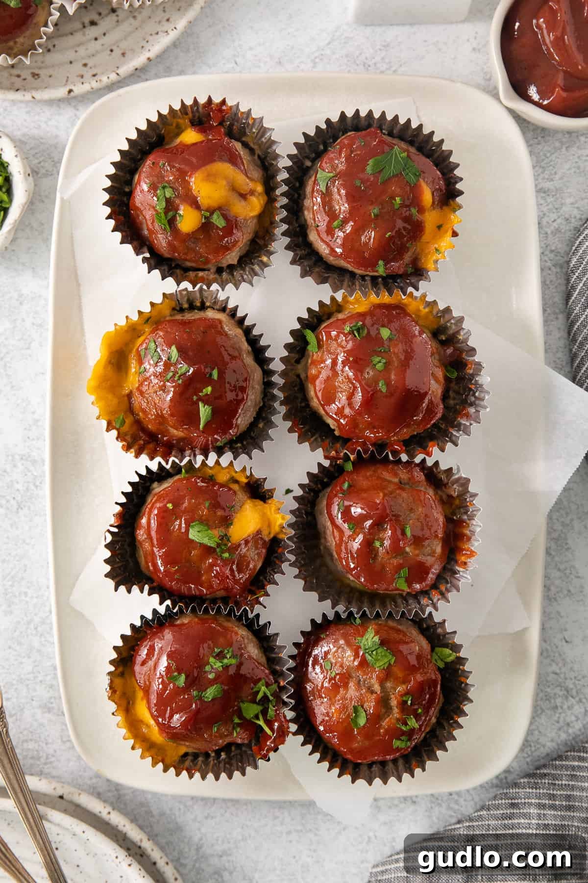 Individual Meatloaf Cups 2 Cheesy meatloaf muffins served on a white plate, ready to be enjoyed.